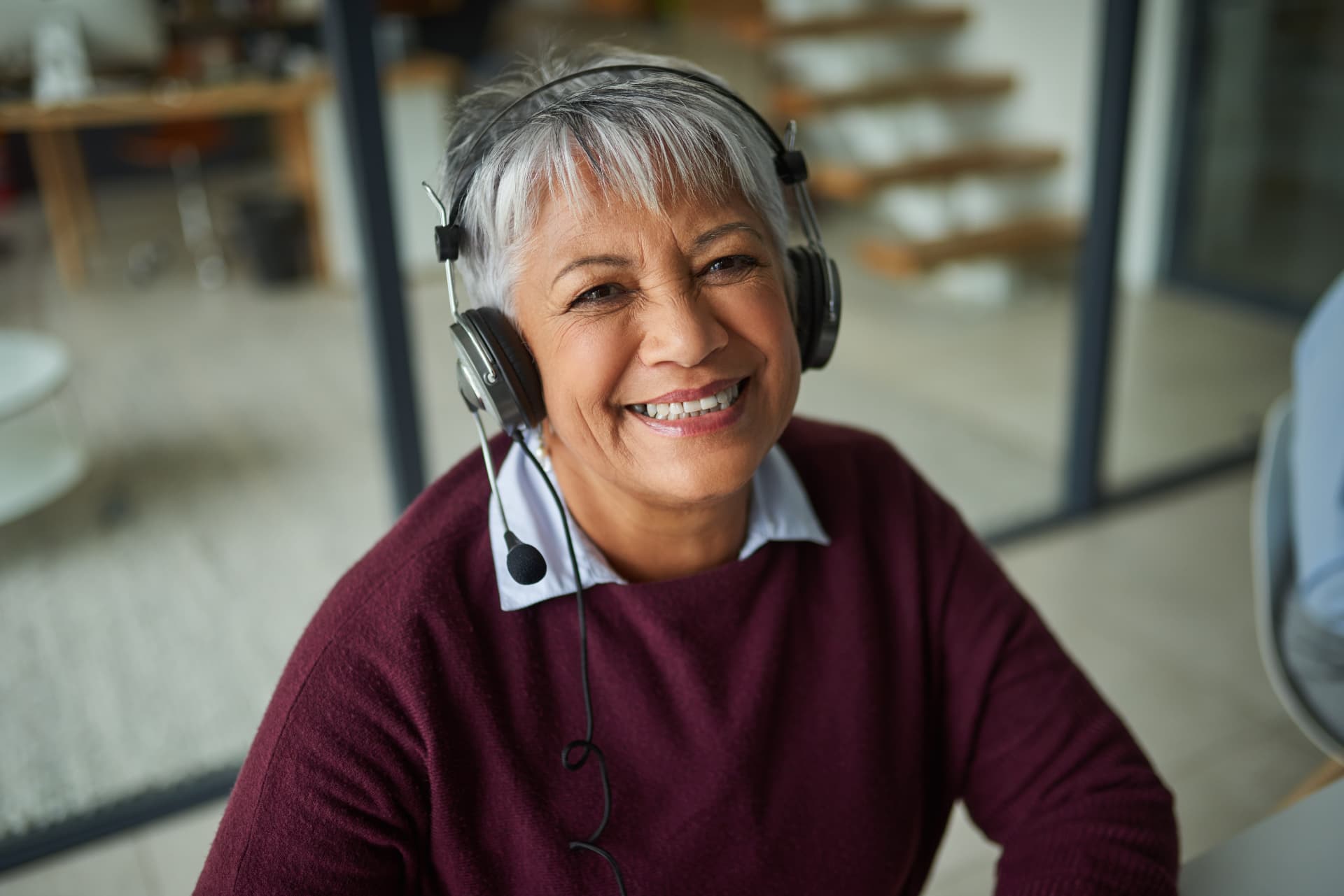 A smiling woman with silver hair wearing a headset