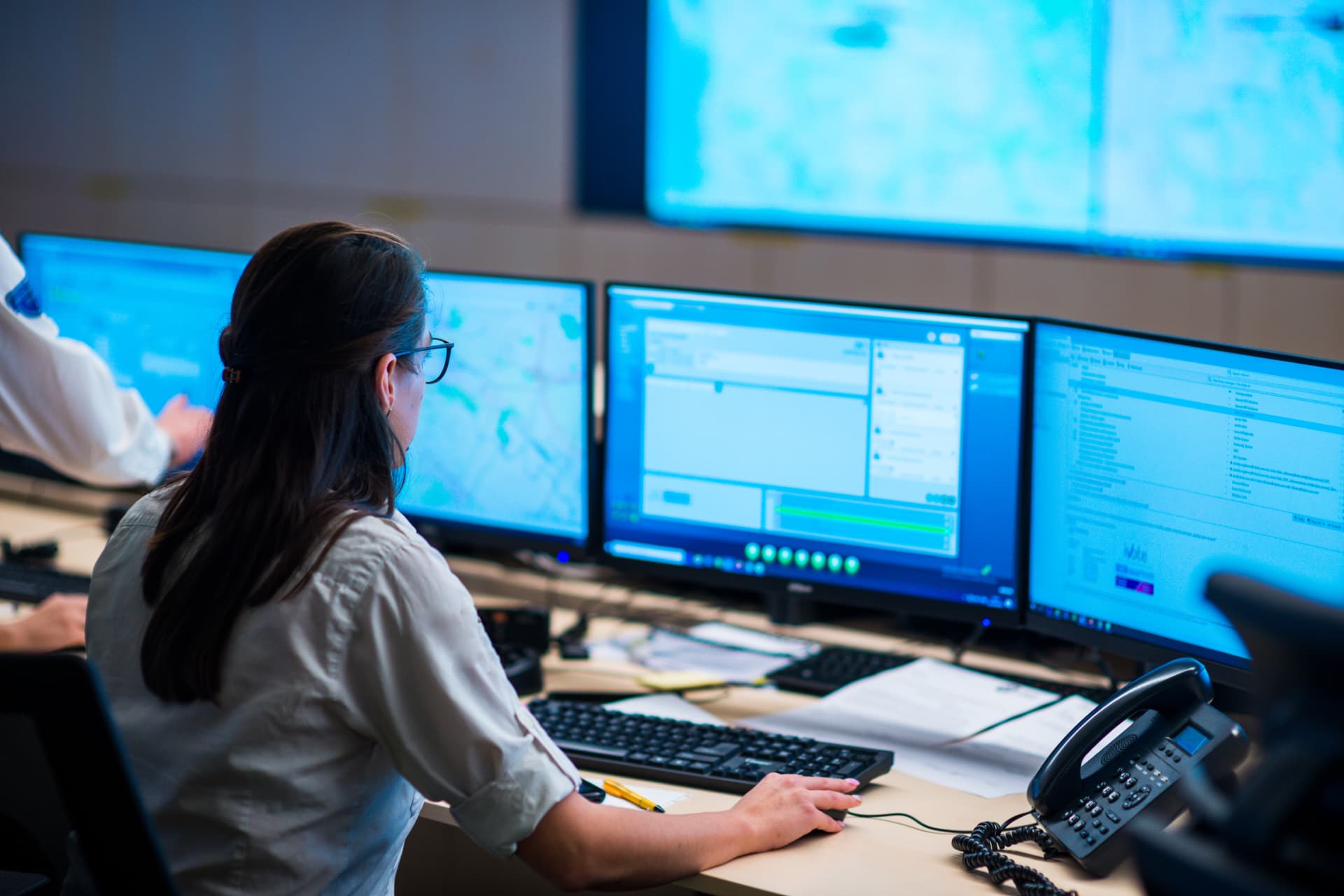 A dispatcher working at several monitors in an operations centre